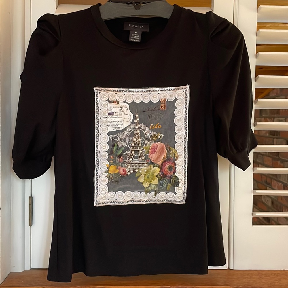 Black puffed sleeve shirt in rayon, nylon and spandex.